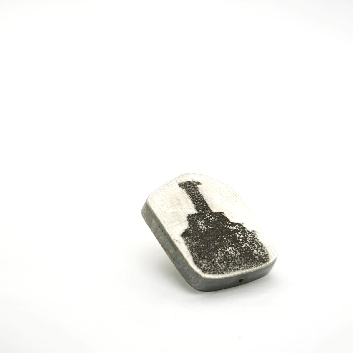 Angled view of a sterling silver pin featuring a bottle motif.