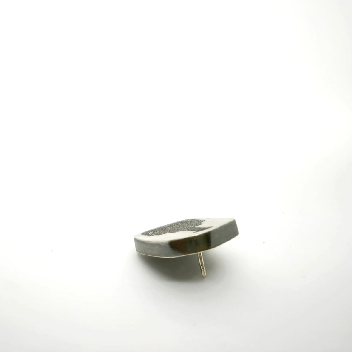 Profile view of a sterling silver pin featuring a bottle motif, showing its depth and fastening post.