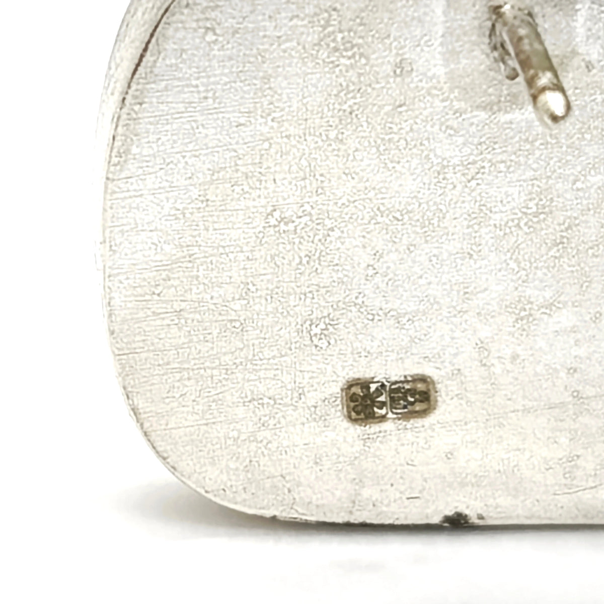 Detail of the hallmark and reverse side of a sterling silver pin from the At the Table collection.
Show more lines