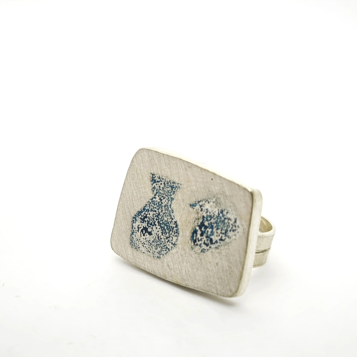 Angled view of a sterling silver ring featuring two jug motifs, by Inês Almeida.