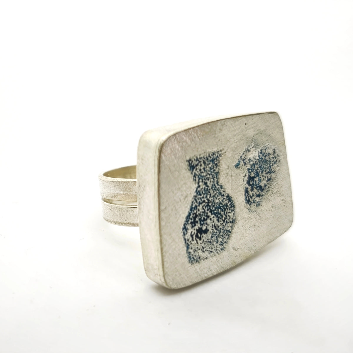 Angled view of a sterling silver ring featuring two jug motifs, by Inês Almeida.