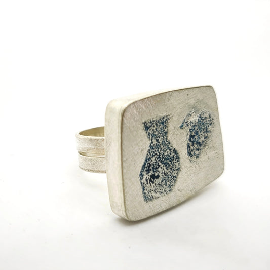 Angled view of a sterling silver ring featuring two jug motifs, by Inês Almeida.