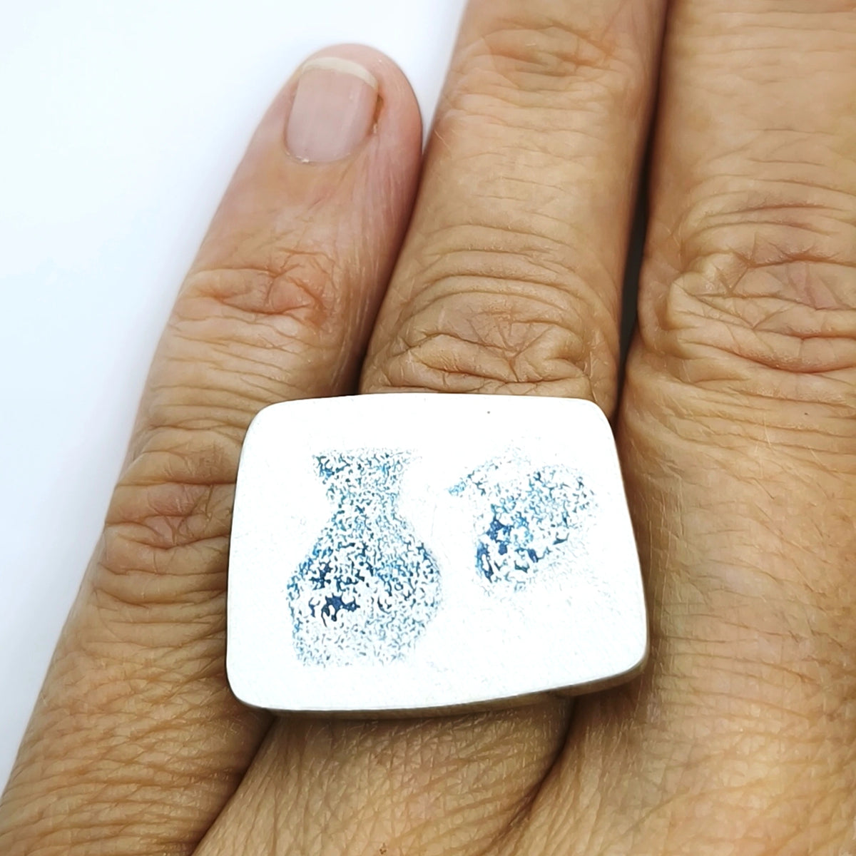 Sterling silver ring featuring two jug motifs worn on a natural hand against a soft white background, from the At the Table with Morandi collection by Inês Almeida.